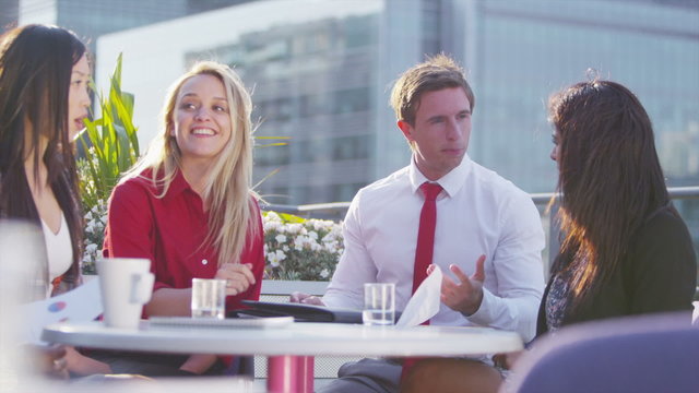 Happy business group sit and chat together on outdoor city roof terrace