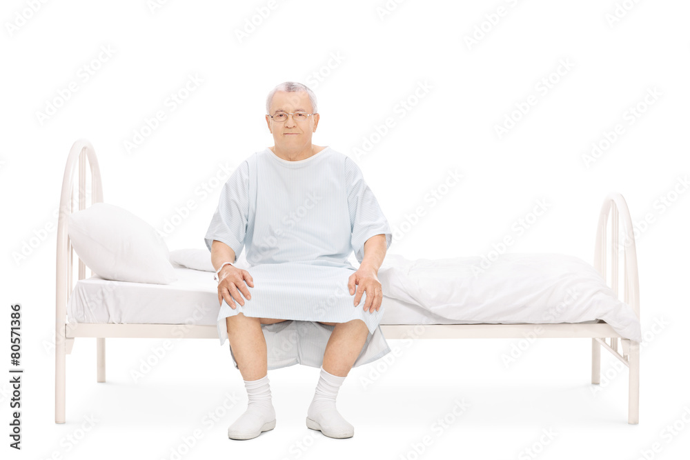 Wall mural mature patient in a hospital gown sitting on a bed