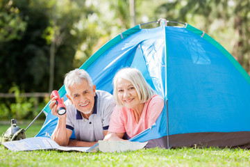 Senior Couple With Map And Torch In Tent