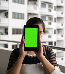 Asian woman holding tablet in front of her face