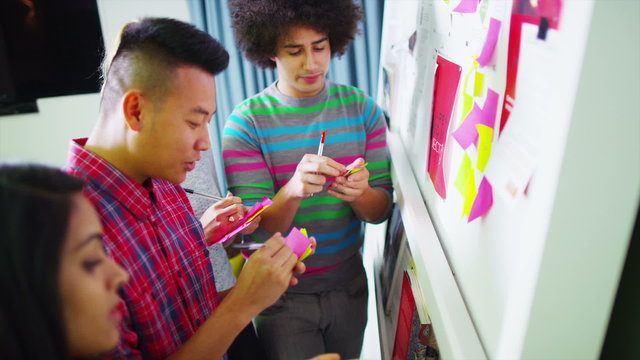 Young creative business team brainstorming with the use of post-it notes