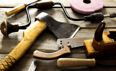 Many old working tools ( axe, saw and others) on a wooden