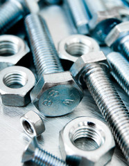 Nuts and bolts on scratched metal background.