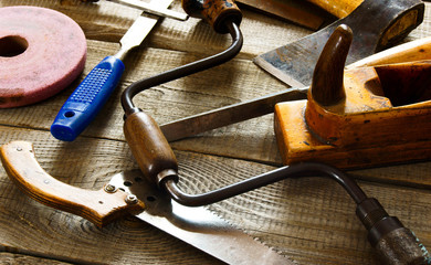 Many old working tools ( saw, plane and others) on a wooden