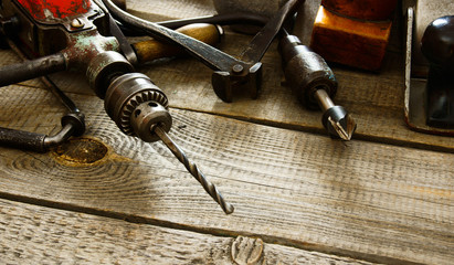 Many old working tools (drill, pliers and others) on a wooden