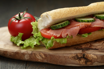 sandwich with salmon and vegetables on wood table