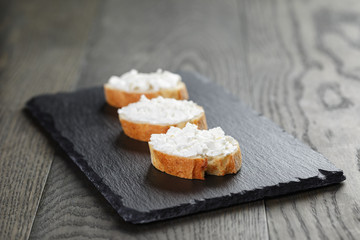 crunchy baguette slices with cream cheese on slate board