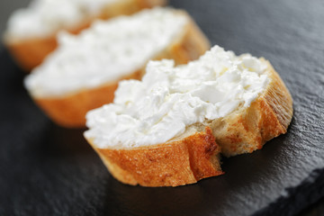 crunchy baguette slices with cream cheese on slate board