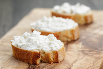 crunchy baguette slices with cream cheese on olive board