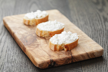 Fototapeta na wymiar crunchy baguette slices with cream cheese on olive board
