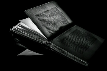High contrast b&w image of an old book on black surface
