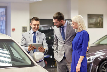 happy couple with car dealer in auto show or salon