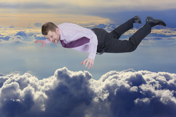 Businessman falling down over clouds in background