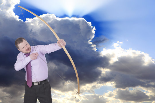 Businessman practicing archery and clouds in background