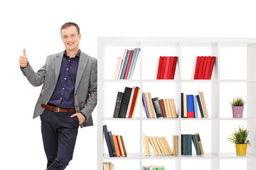 Guy leaning on a bookshelf and giving a thumb up