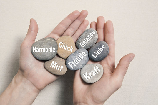 Hände halten Steine mit Glück, Mut, Kraft, Freude, Harmonie