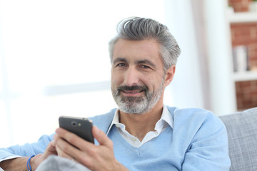 Obraz na płótnie Canvas Mature man sending message with smartphone