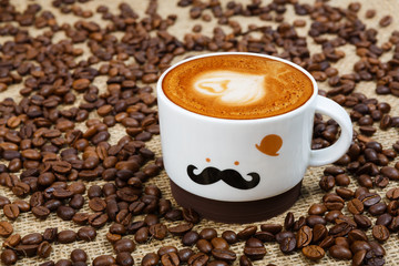 Coffee cup and beans on sacking background