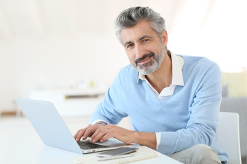 Trendy mature man working from home with laptop