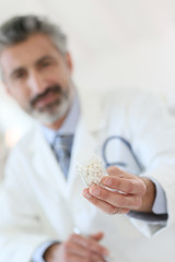 Obraz premium Mature doctor in hospital giving pills to patient