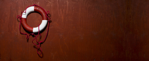 Red and white life buoy hanging on the side of a wood