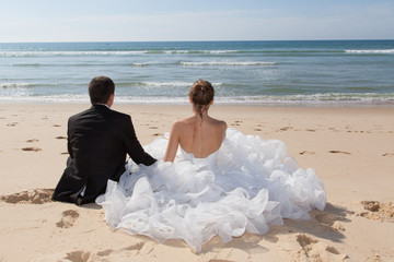 Fototapeta na wymiar Bride and groom sitting on the beach
