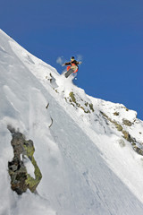 Naklejka na ściany i meble Snowboarder sprigt in einen Tiefschneehang