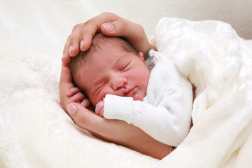 Baby schläft ruhig und zufrieden in Mutterhänden