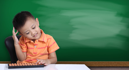 Little boy playing  abacus with green chalk board background