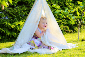 Preschooler girl playing in the garden hiding in tent © cromary