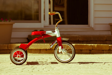 Child's rusted red tricycle standing ready