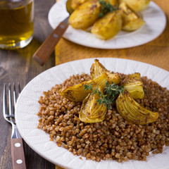 Buckwheat porridge with baked onions on a wooden table
