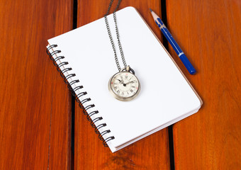 Diary and pocket watch  on wooden table