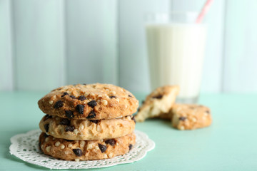 Tasty cookies and glass of milk on color wooden background