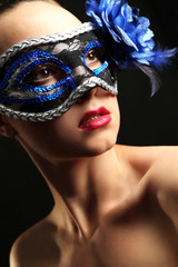 Naklejka premium Portrait of beautiful woman with fancy glitter makeup and Masquerade mask on dark background