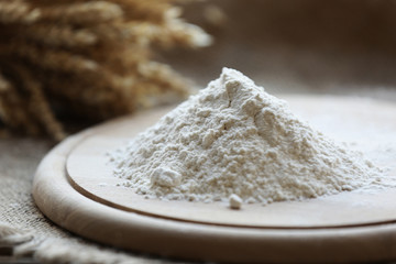 Pile of flour on cutting board with burlap cloth, closeup