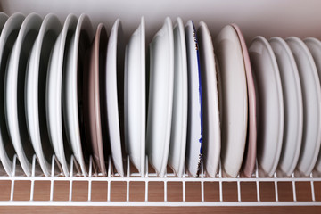 Clean plates drying on metal dish rack on shelf