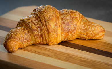 Single croissant on wood cutting board