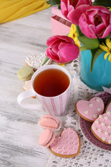 Composition of spring flowers, tea and cookies on table