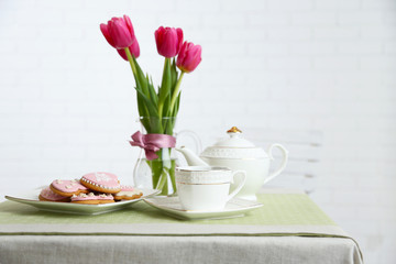 Fototapeta na wymiar Tea set with flowers on table, on light background