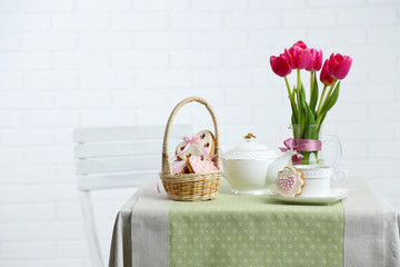 Tea set with flowers on table, on light background
