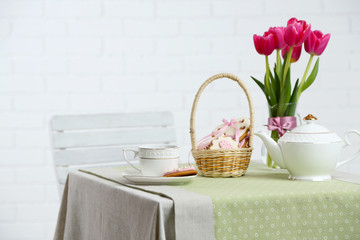 Tea set with flowers on table, on light background