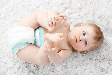Cute baby boy on carpet, on light background