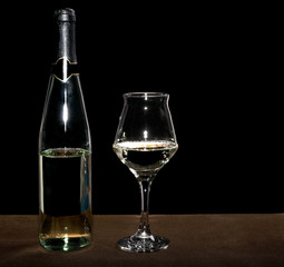 White wine bottle and filled wineglass closeup