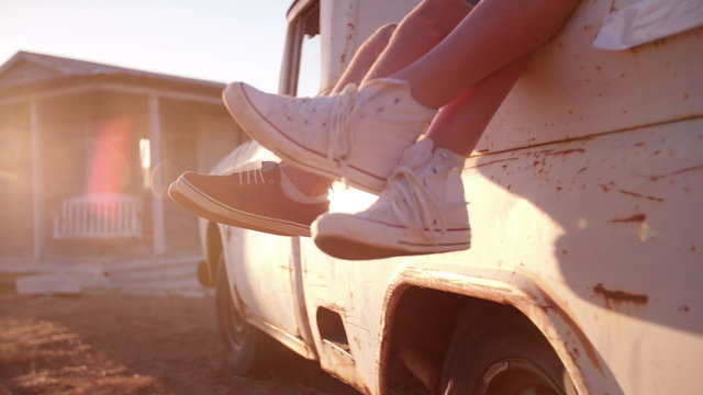 Teen couple's legs hanging out of vehicle with sun flare