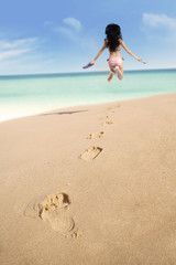 Fototapeta na wymiar Footprints on sand and jumping woman