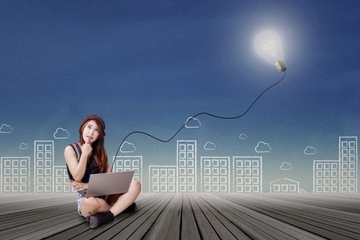 Teenage girl with laptop daydreaming