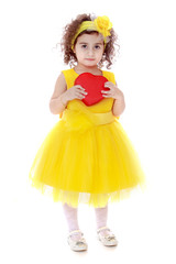 Girl in yellow dress holding red heart
