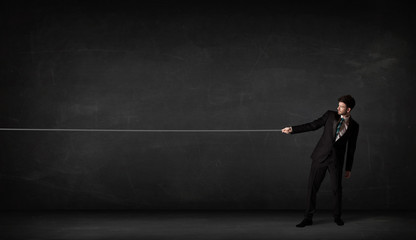 Businessman pulling rope on grey background