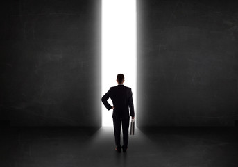 Business person looking at wall with light tunnel opening